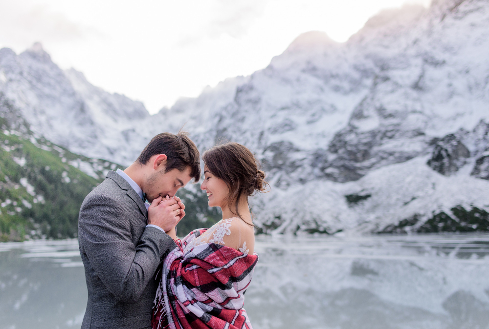 wedding couple is warming up together in the winter mountains